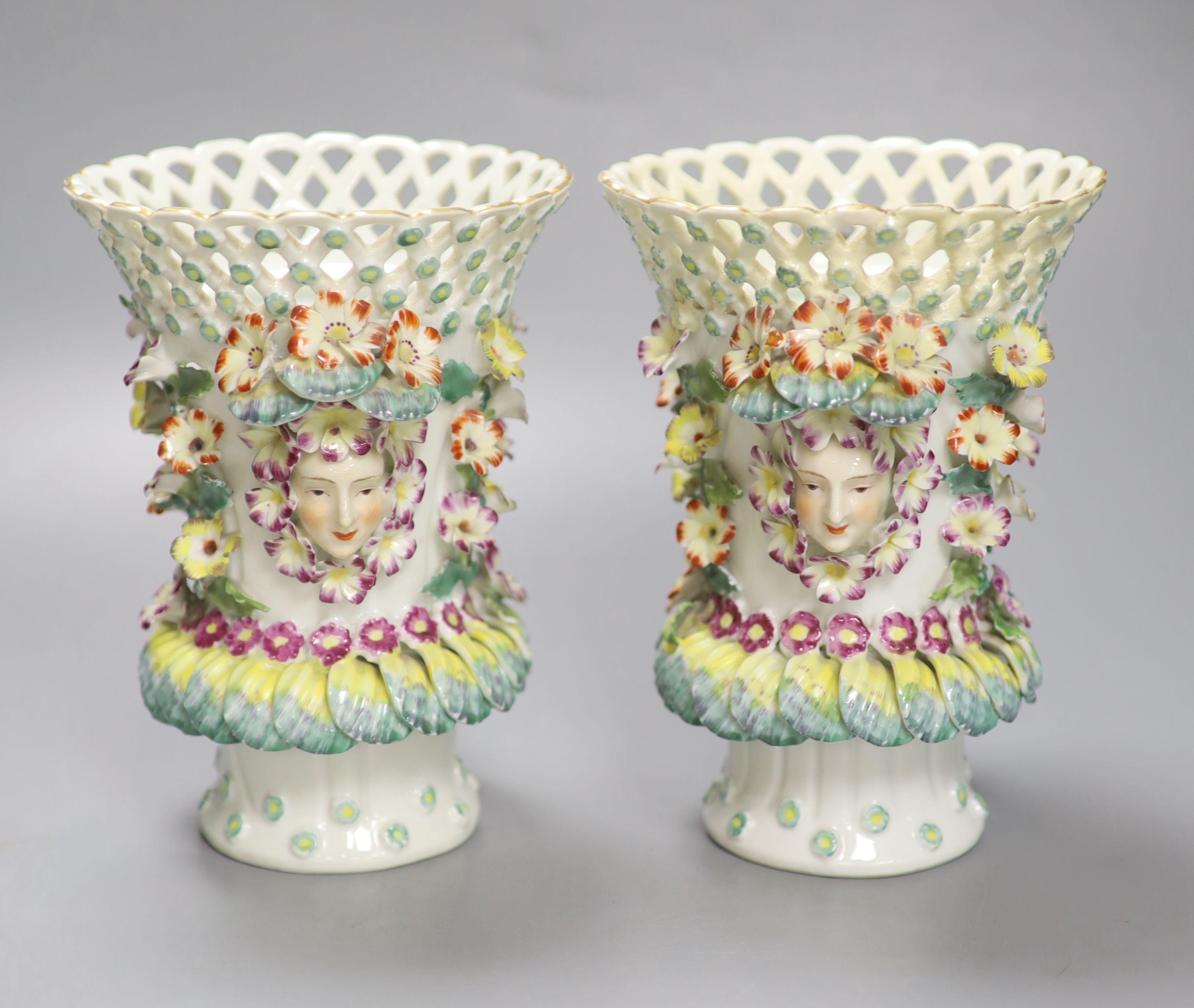 A pair of Continental frill vases with pierced necks and applied mask heads encrusted with flowers, height 18cm